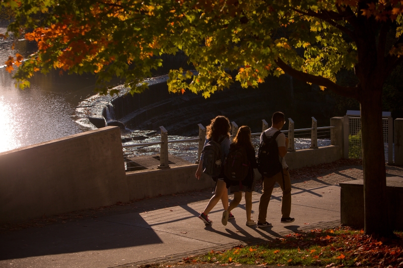 Students walk across Triphammer Foot Bridge in fall. 